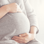 Mujer embarazada, sentada tocando su vientre