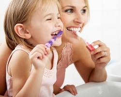 Mamá explicando cepillado dental a su niña